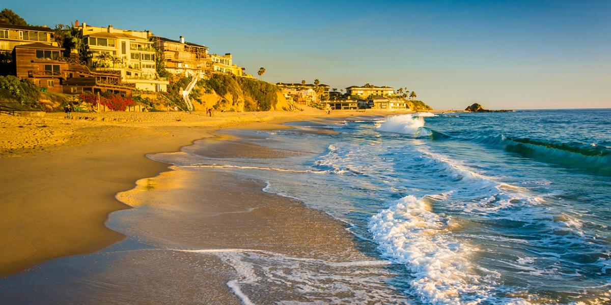 Beautiful image with the waves crashing on the shore and a line of houses in the background