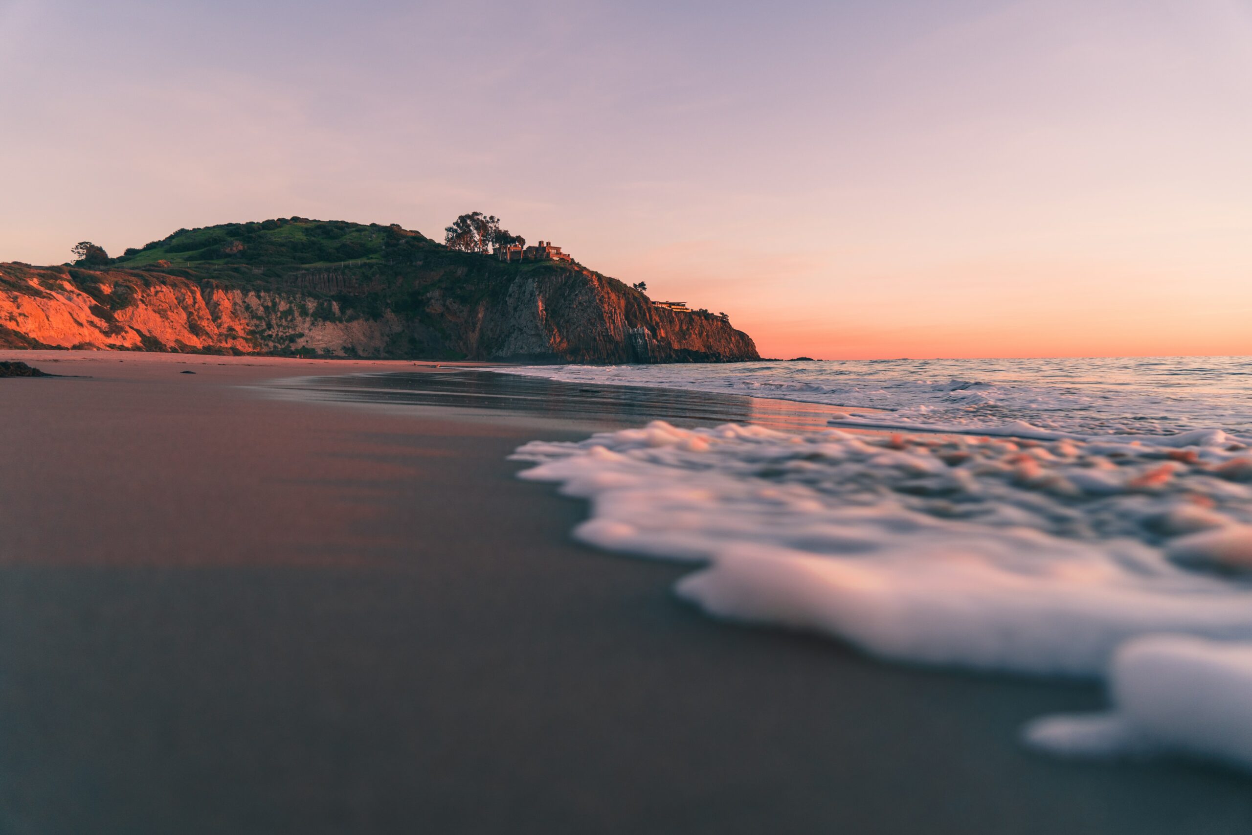 Beach at Dusk with Water Crashing in and Cliff in Background