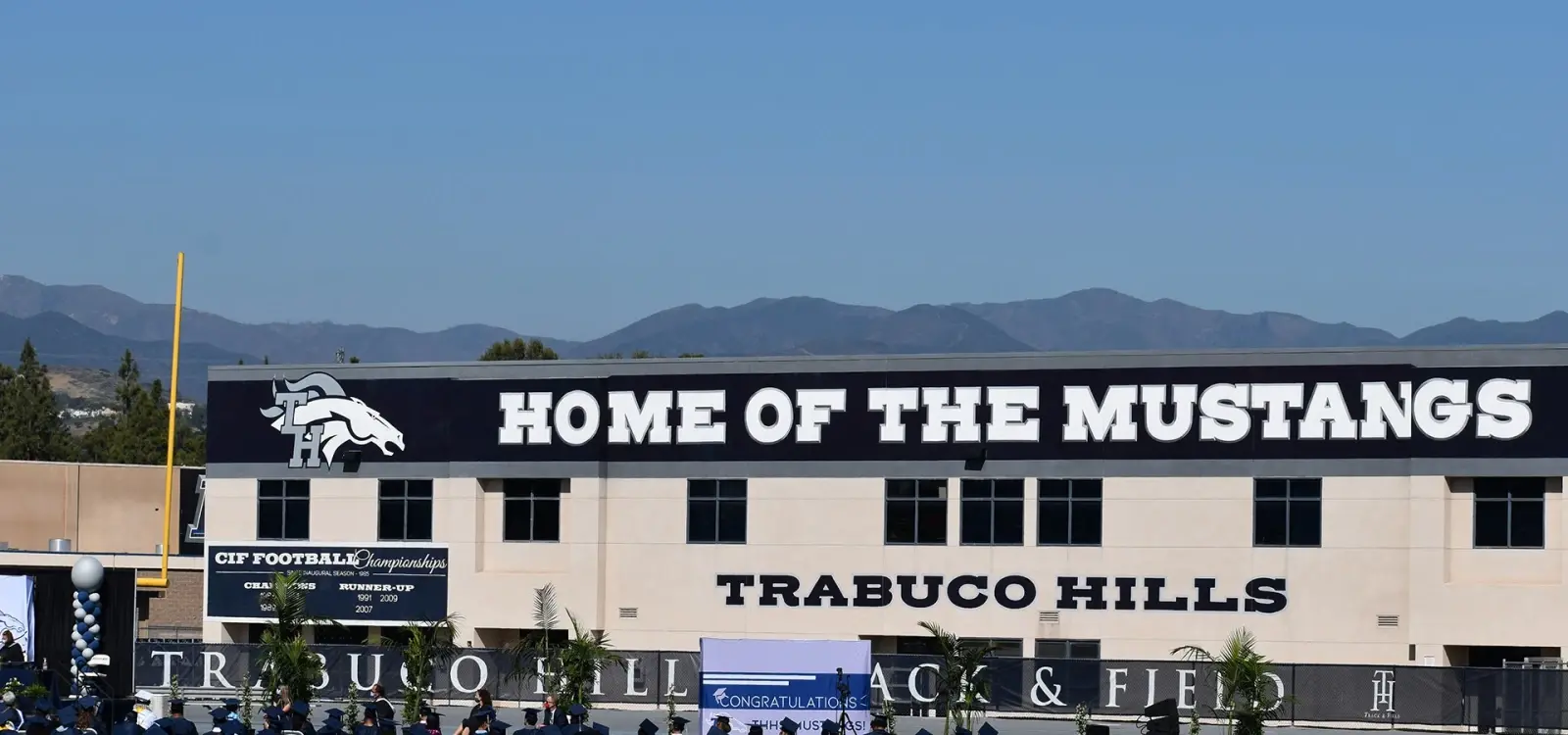 Graduating Class with Trabuco Hills High School and Home Of The Mustangs Sign on School Building in the Background