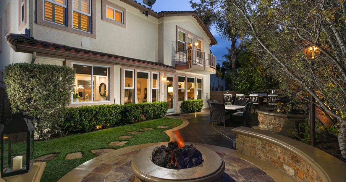 Luxurious Laguna Niguel backyard at dusk featuring a fire pit and patio dining area, showcasing prime real estate in Orange County, CA.