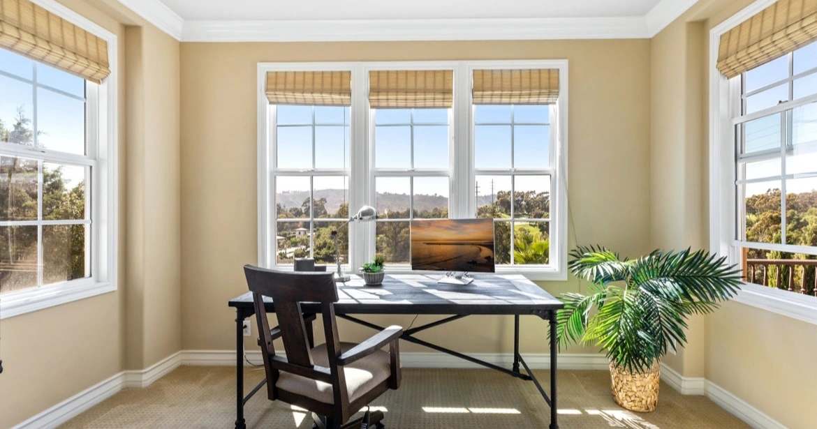 Sunlit home office with panoramic views of Laguna Niguel landscape and trees, showcasing the serene beauty of Orange County real estate.