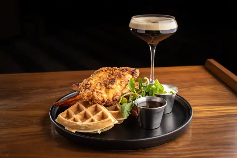 Plate of Fried Chicken and Waffles, Sweet Potato Fries, Microgreens, Two Dipping Sauces, and an Espresso Martini fro Julep Cast Iron Kitchen in Brea