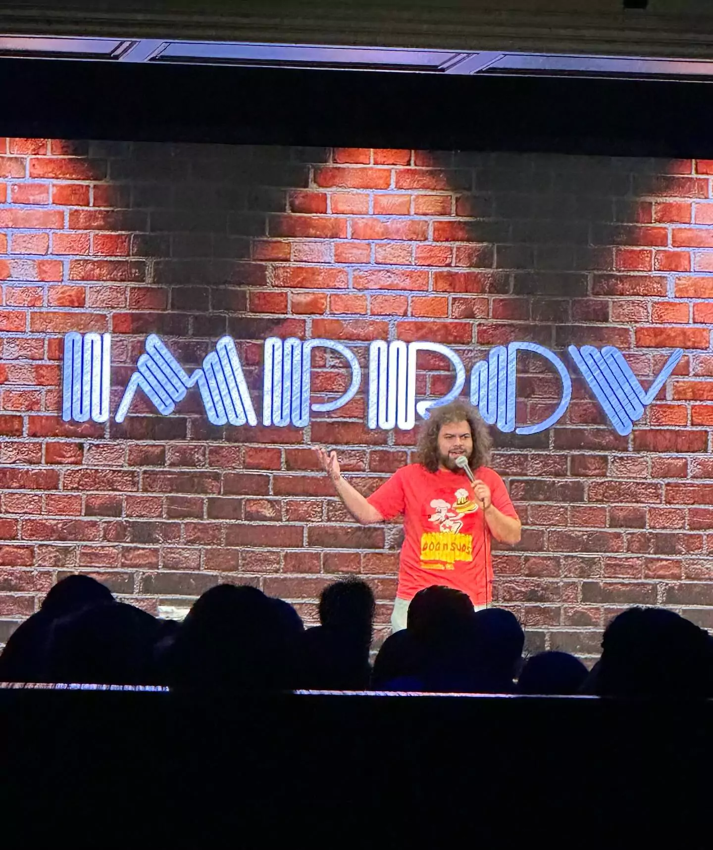 comedian with red graphic t shirt performing at brea improv