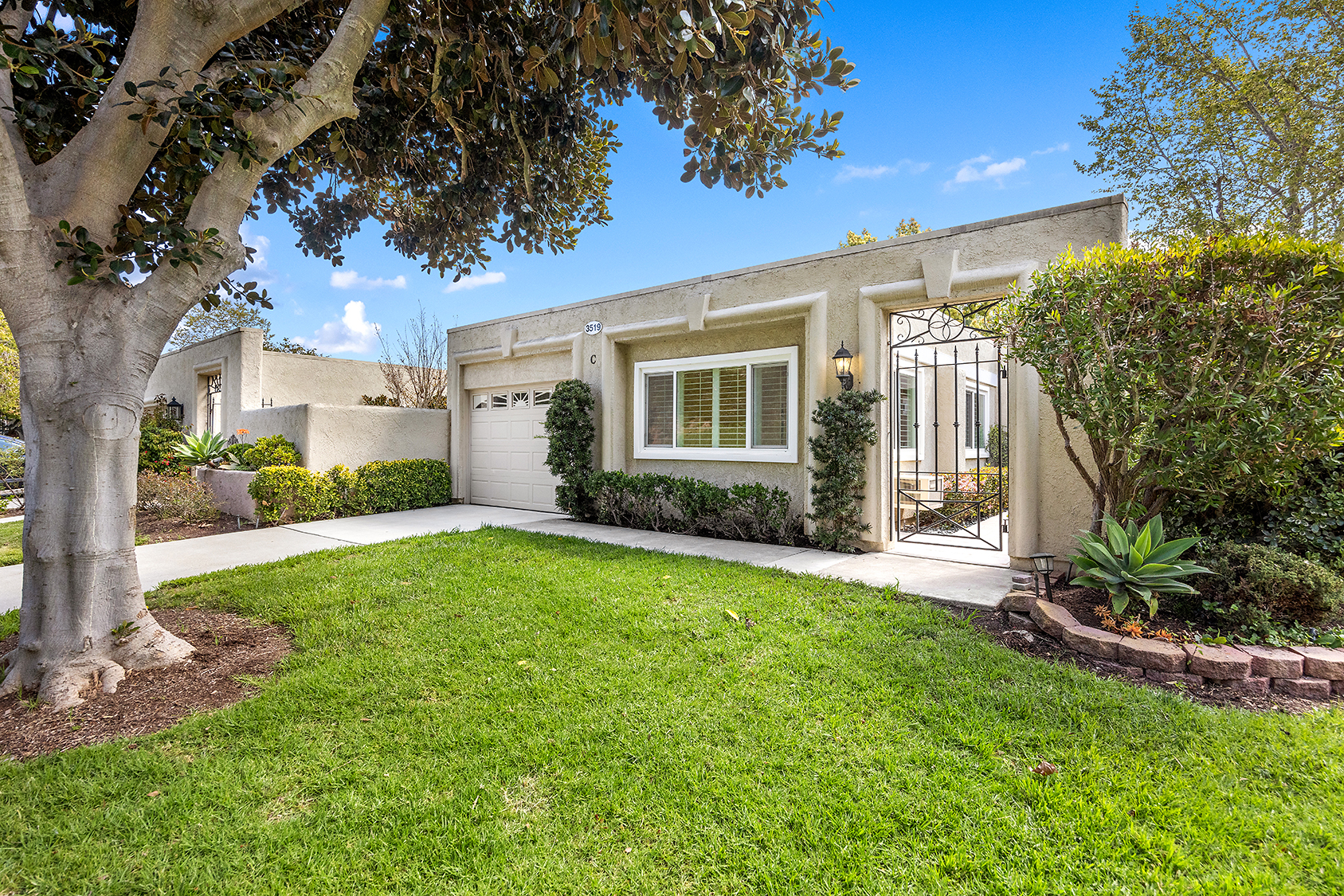 Front exterior of a Laguna Woods Village condo with gated courtyard and garage