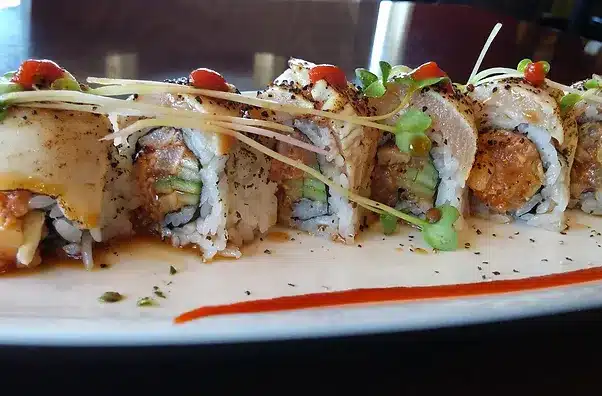 Close Up View of Sushi with Tuna and Cucumber and topped with Microgreens and Red Sauce from Fish In A Bottle