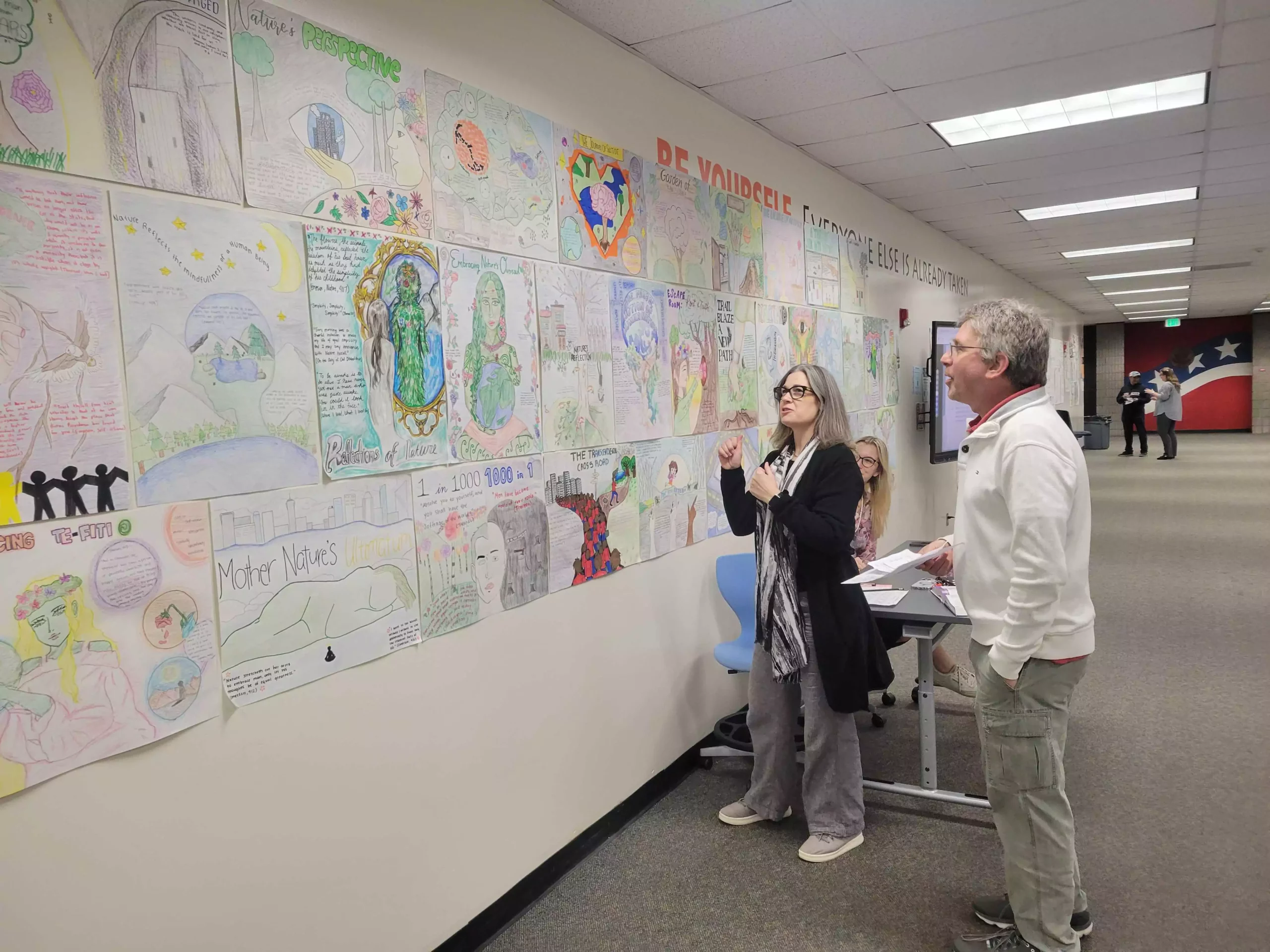 Two Parents looking at Wall Full of High School Students’ Drawings at Cypress High School