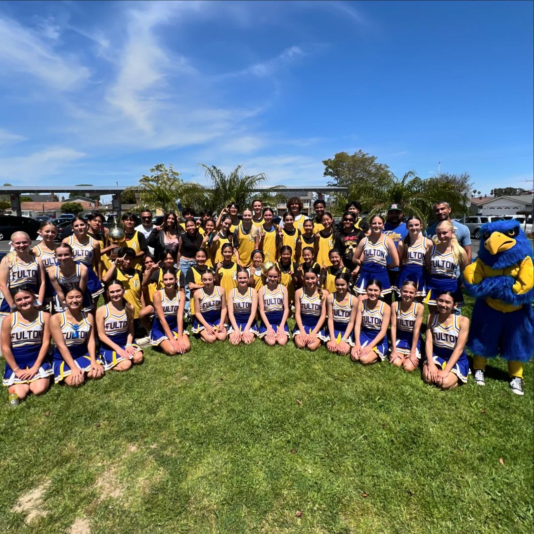 Cheerleaders, women’s basketball team, and men’s basketball team posing in a semi circle on a lawn who are students at Fulton Middle School