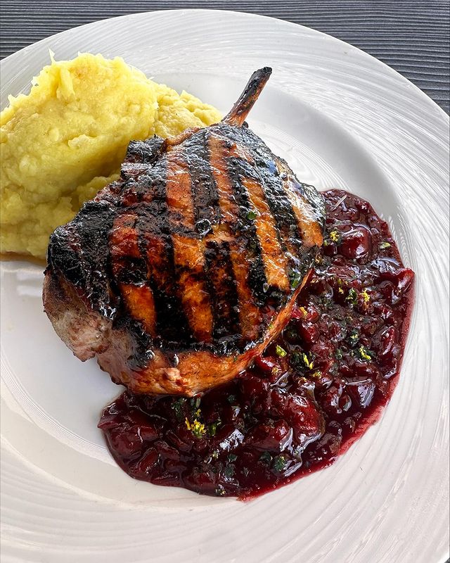 Bone In Pork Chop topped with a cherry cabernet sauce and orange gremolata, served with maple mashed sweet potatoes from Summit House