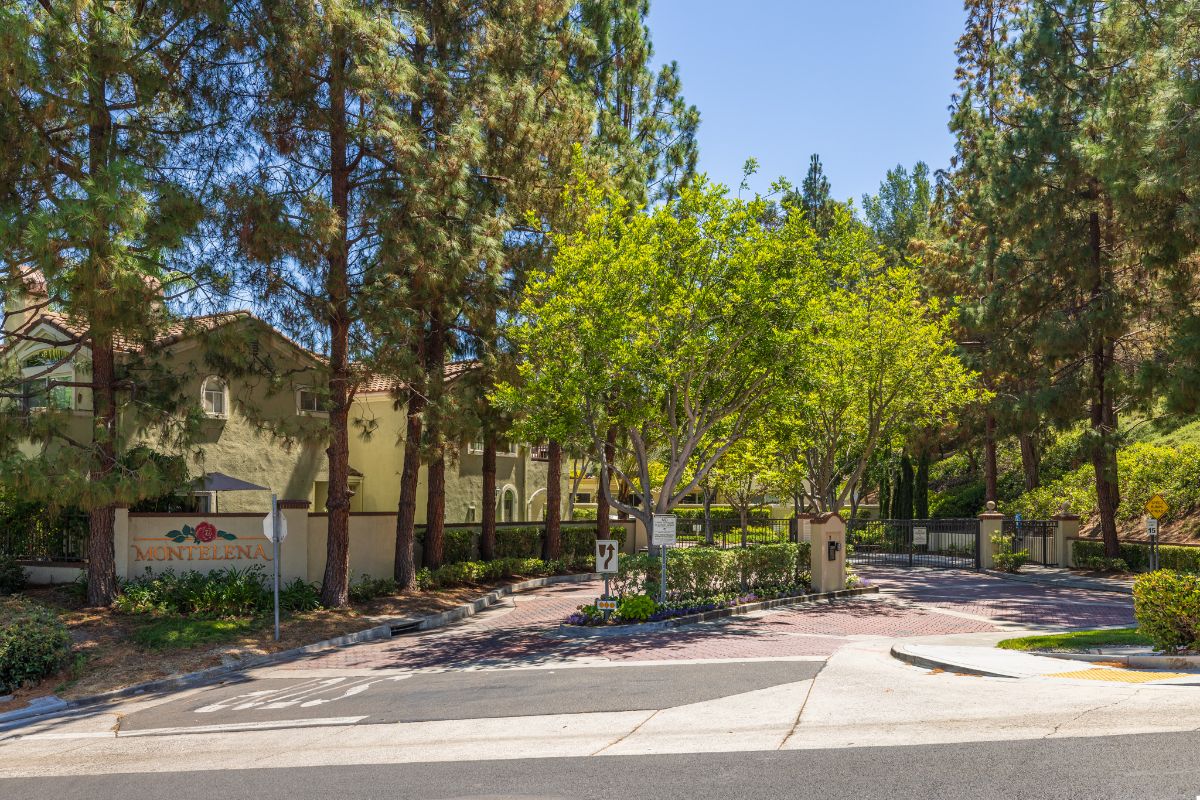 Entry gate and drive surrounded by trees, leading into the Montelena gated community in Aliso Viejo