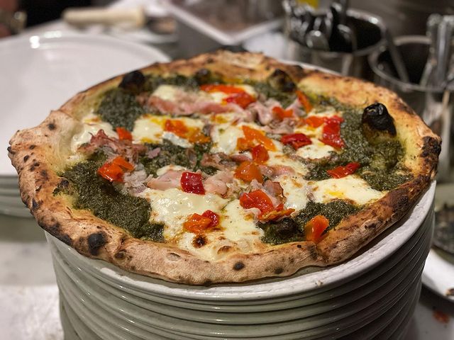 Wood Fired pizza pie topped with smoked provolone, porchetta, pickled peppers, and a green pesto from Fuoco