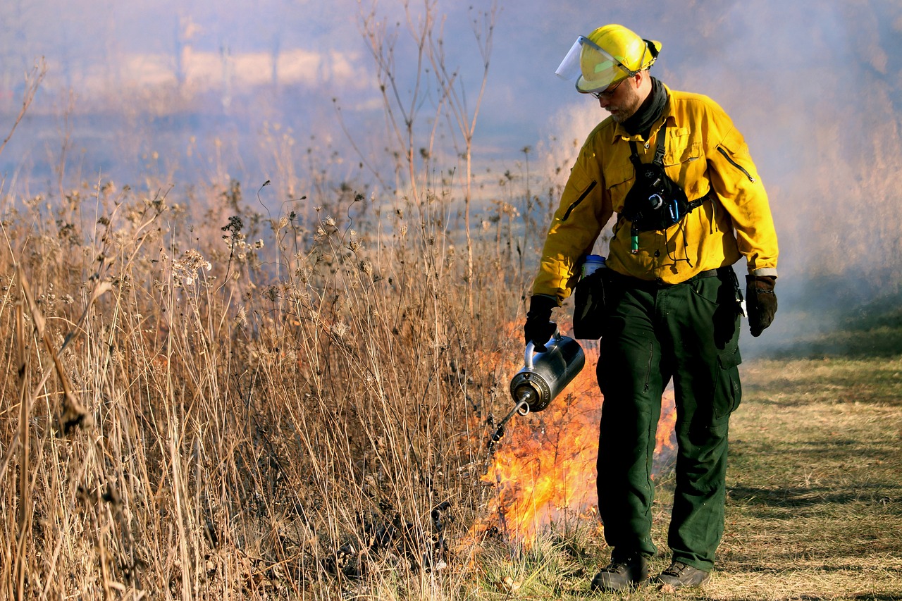 Firefighter conducting a controlled burn in Laguna Hills, Orange County to mitigate wildfire risk and prevent home insurance damage amid California's homeowners insurance crisis. The Brad Feldman Group, top Laguna Hills real estate agents, help clients navigate insurance challenges when buying or selling luxury properties.