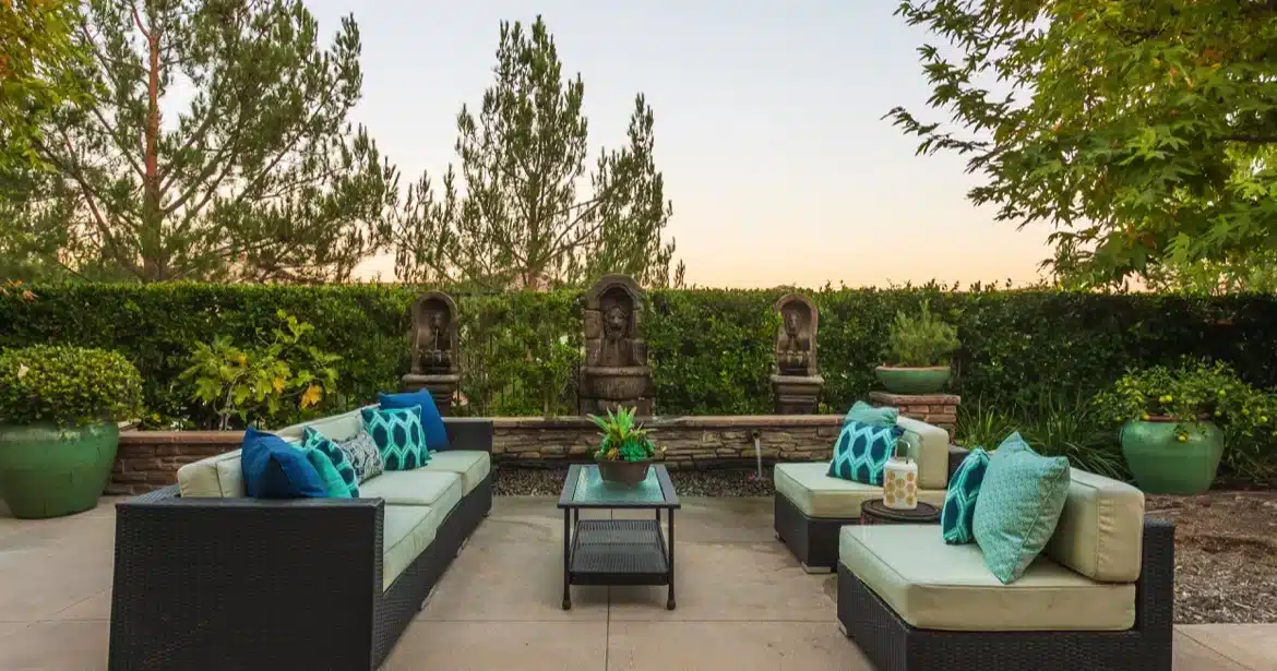 Luxurious outdoor living area in an Aliso Viejo home, complete with sculptures and privacy hedges, ideal for enjoying the mild autumn climate in Southern California.