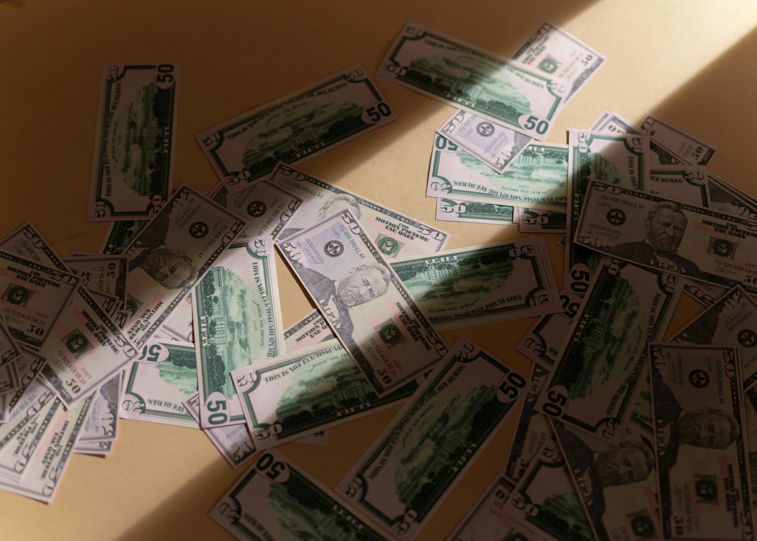 Dollar bills on a beige surface, representing closing costs in Laguna Hills for home sellers by top local real estate realtor agents Brad Feldman Group