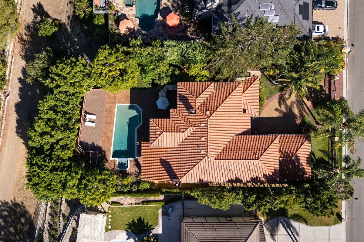 Aerial drone image of home with tile roof and backyard pool