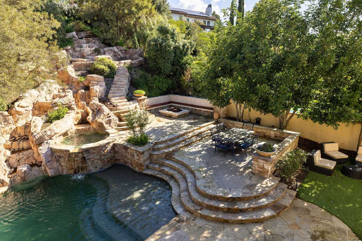 Backyard with stone hardscape and stairs with landscaping surrounding a pool in a luxury home in Nellie Gail Ranch, listed by Brad Feldman Group the best OC realtors
